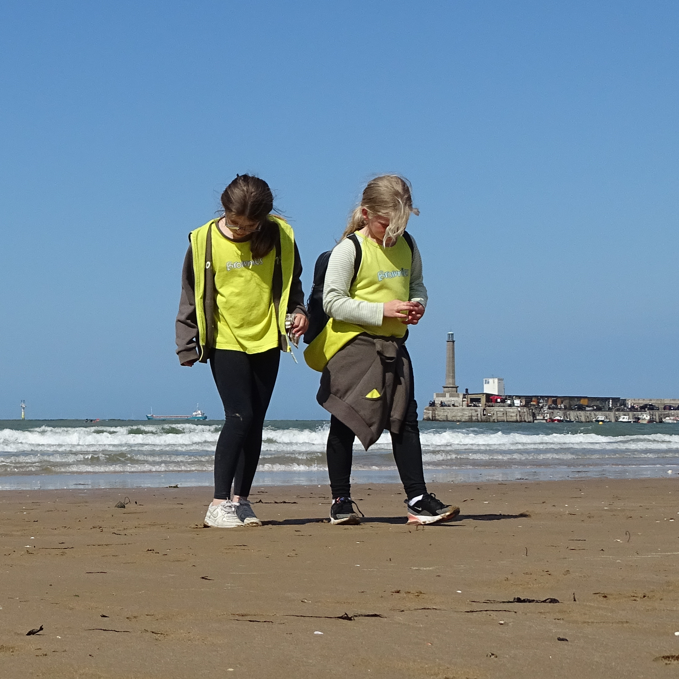 2 Brownies walking on the beach at Margate with the lighthouse in the background.