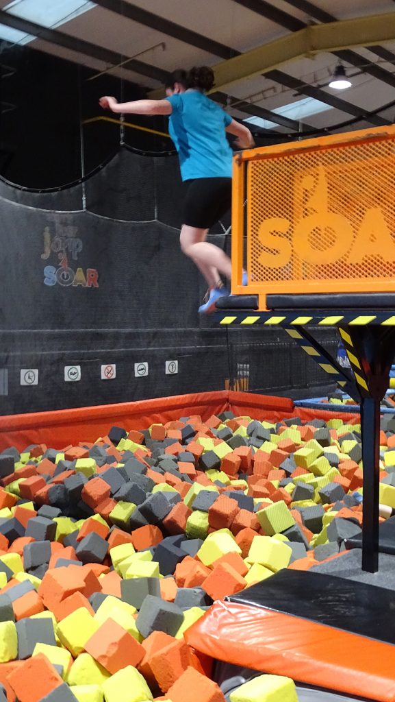 A Ranger jumps from a high platform into foam cubes at Soar trampoline park.