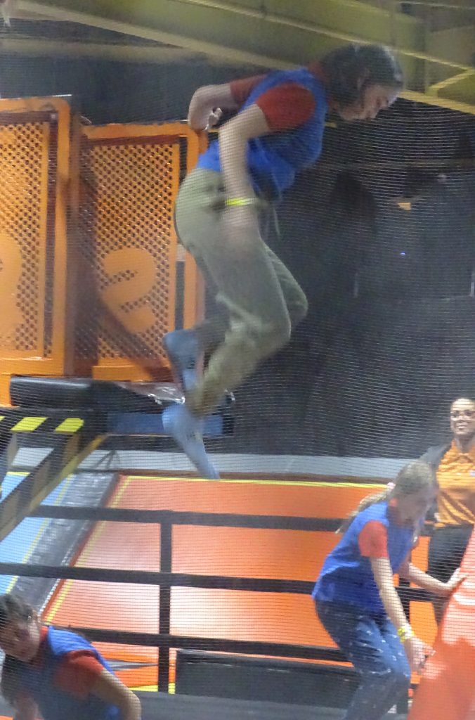 A Guide jumps from a high platform into foam cubes at Soar trampoline park.